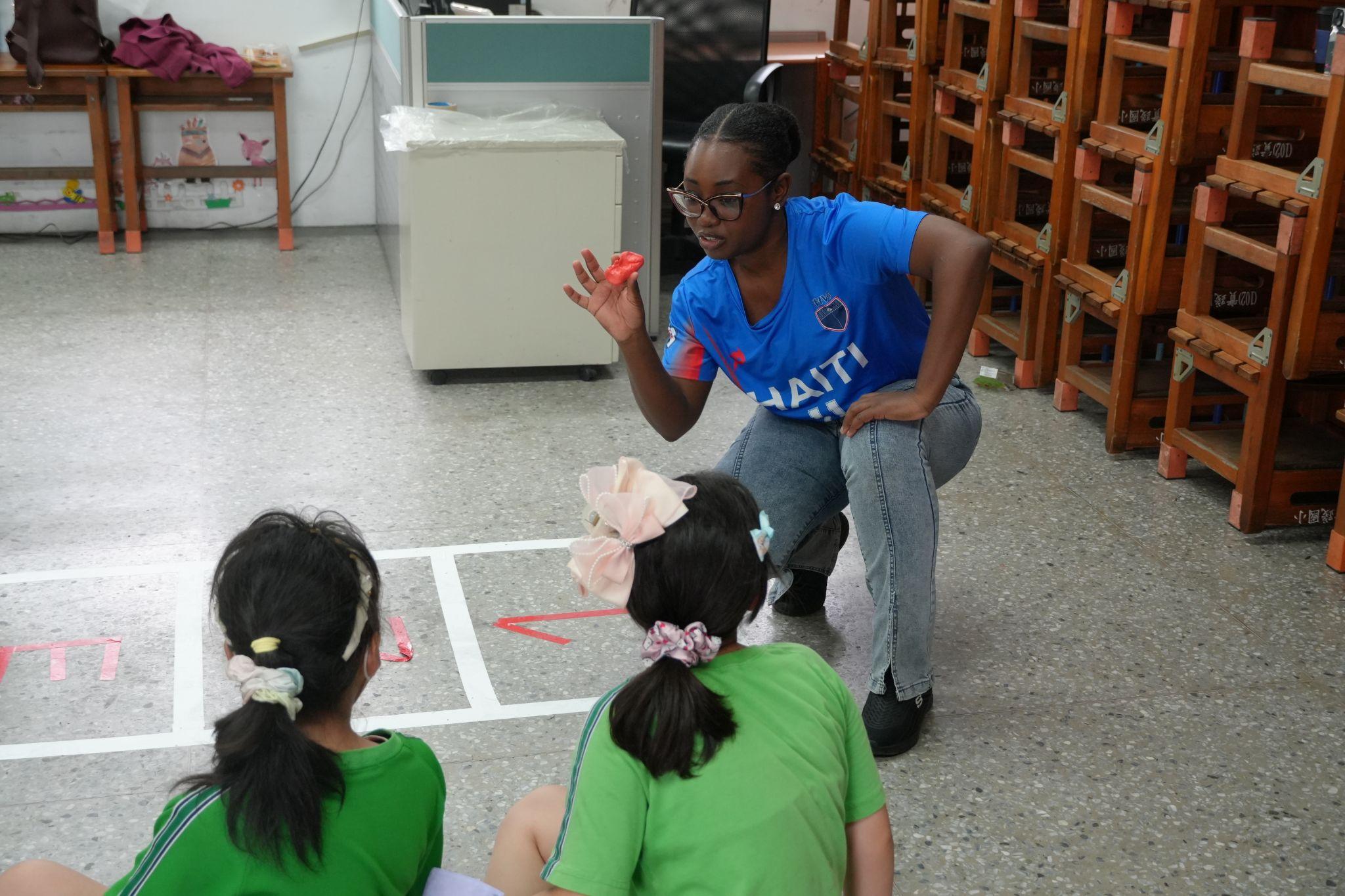 Haitian participant Adneissa Christy introduces the rules of the hopscotch game to students. (Photo credit: ICI)